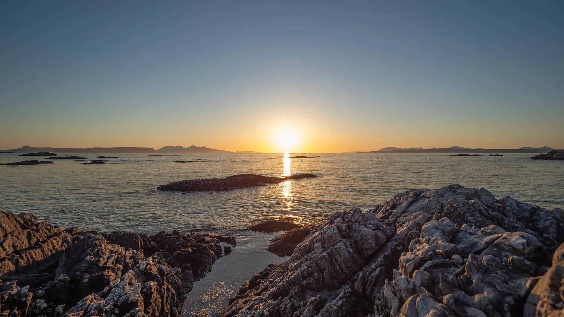 Sunset over the Scottish coast with islands on the horizon